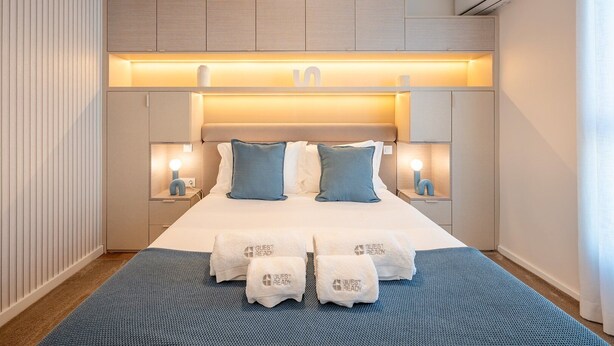 Een moderne hotelkamer met een groot bed, nachtlampjes en een vastgezet hoofdeinde.