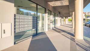 Een modern gebouw met grote glasramen, een overdekte doorgang en een rij brievenbussen.
