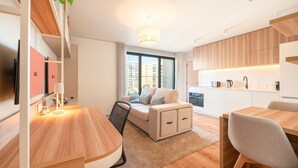 Eine moderne Wohnung mit Essbereich, einer Couch, einer Küche und einem großen Fenster.