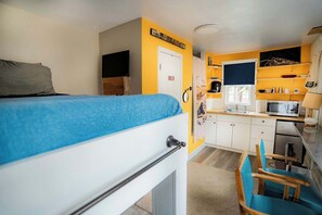 Una habitación compacta con cama, kitchenette, un pequeño comedor y baño.