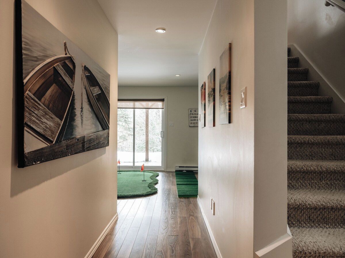 A hallway with wooden flooring, a staircase, and a view to a deck area.