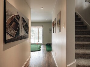 A hallway with wooden flooring, a staircase, and a view to a deck area. - MiniPutt ~ Arcade ~ Pool ~ Playground ~ Golf & Ski (Mont-Tremblant)