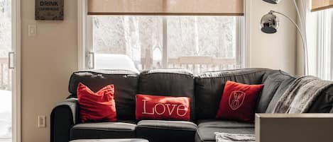A living room with a sectional sofa, red cushions, a coffee table, and a wall-mounted lamp.