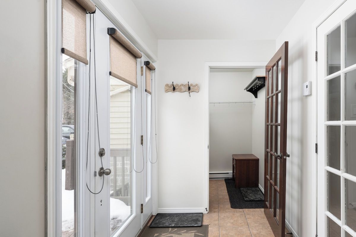 A hallway with a door leading to a room, a small wooden bench, and a wall-mounted decoration.