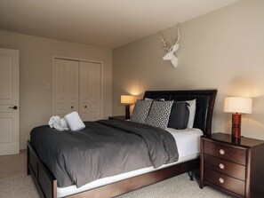 A bedroom with a bed, bedside tables, a wall-mounted deer head decoration, and a door. - MiniPutt ~ Arcade ~ Pool ~ Playground ~ Golf & Ski (Mont-Tremblant)