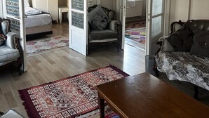 Une pièce comprenant un lit, un canapé, une table en bois et une chaise. Un lustre est suspendu au plafond.