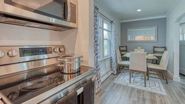 A modern kitchen with stainless steel appliances, a dining area with a table and chairs, and a patterned rug. - Beach Goer’s Paradise (Luna Pier)