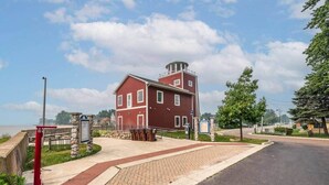A red brick building with a tower, a paved walkway, and a road. - Beach Goer’s Paradise (Luna Pier)
