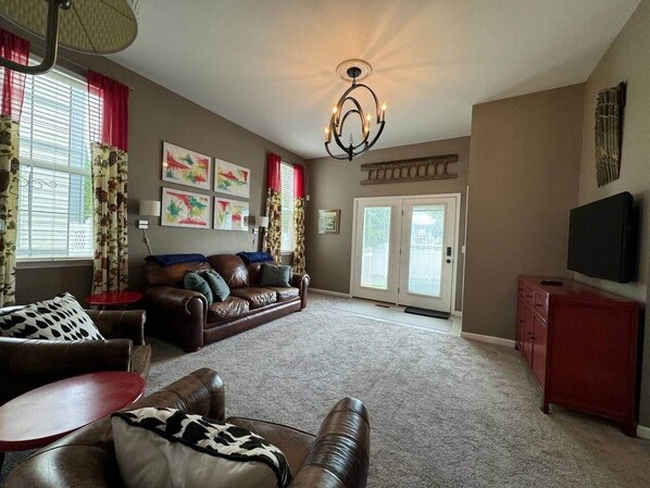A living room with a brown leather sofa, a red side table, and a television on a stand. - The Battlefield Getaway (Monroe)