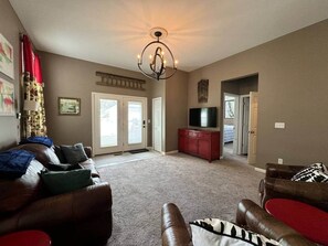 A living room with a brown leather sofa, a red cabinet, and a television. - The Battlefield Getaway (Monroe)