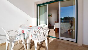 Ein Balkon mit Tisch und Stühlen, eine Glastür und ein Blick ins Freie.