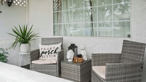 Un espace extérieur accueillant, aménagé avec des fauteuils en osier, une plante en pot et des objets décoratifs.