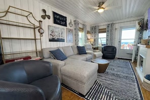 A living room with a sectional sofa, a black armchair, a round coffee table, and a patterned rug.
