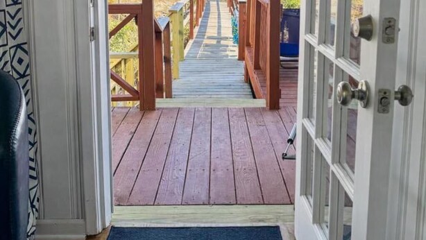 A wooden deck leading to a beach with a clear view of the ocean.