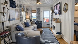 A nautical-themed living room with a sofa, armchairs, a fireplace, and nautical decor.