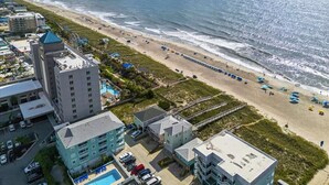 A coastal hotel with multiple buildings, a beach, and a pier.