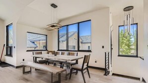 Un'ampia sala da pranzo con un tavolo e sedie capienti, ampie finestre con vista e una moderna lampada a sospensione.