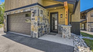 Una moderna casa a due piani con garage, dettagli in pietra e rivestimento in legno.