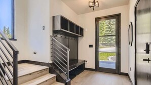 Un interno moderno con una scala, una panca integrata, una porta che dà sull'esterno e un elettrodomestico in acciaio inossidabile.