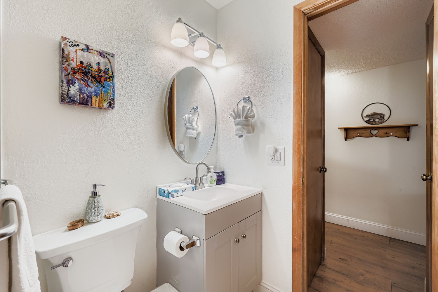 Een badkamer met toilet, wastafel, spiegel en een handdoekhouder.