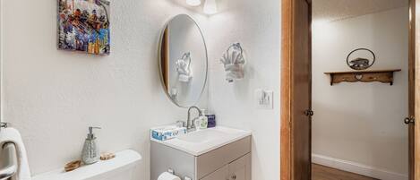 Een badkamer met toilet, wastafel, spiegel en een handdoekhouder.
