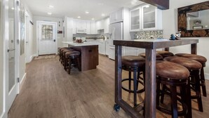 Una cucina moderna con mobili bianchi, un'isola centrale e sgabelli da bar.