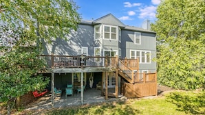 A two-story house with a covered patio, a wooden deck, and a staircase leading to an upper level. - The Yellow House - hot tub, pool table, fire pit, 6 bedrooms (Liberty)