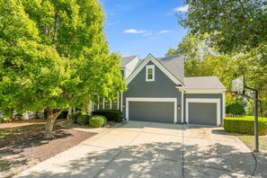 A two-story house with a gray exterior, two garage doors, and a basketball hoop in the driveway. - The Yellow House - hot tub, pool table, fire pit, 6 bedrooms (Liberty)