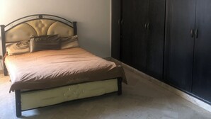 A bedroom with a bed, a wardrobe, and a pendant light. - Guest ROOM (Rabat)