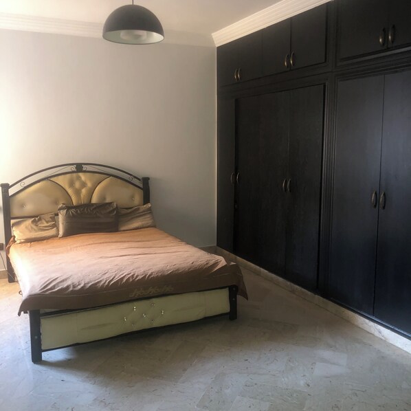 A bedroom with a bed, a wardrobe, and a pendant light. - Guest ROOM (Rabat)