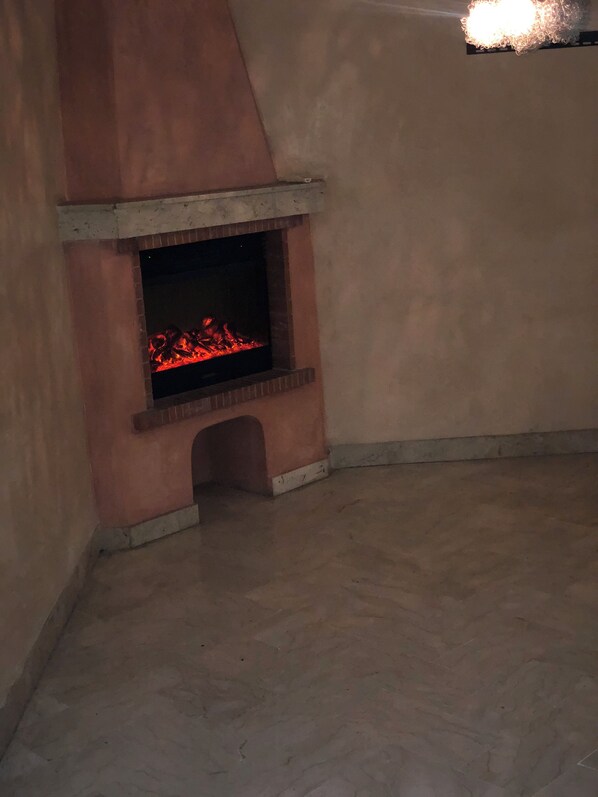 A room with a fireplace, a window, and a tiled floor. - Guest ROOM (Rabat)