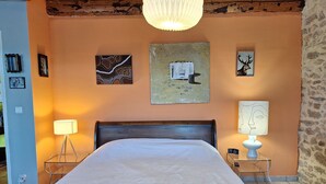 Ein Schlafzimmer mit einem Bett, zwei Nachttischen, einer Lampe und Wandbildern.