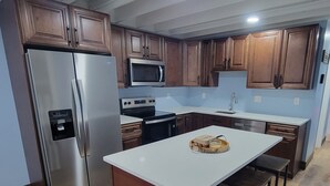 Eine moderne Küche mit Holzausstattung, Edelstahlgeräten und einer zentralen Kochinsel mit Sitzgelegenheiten.