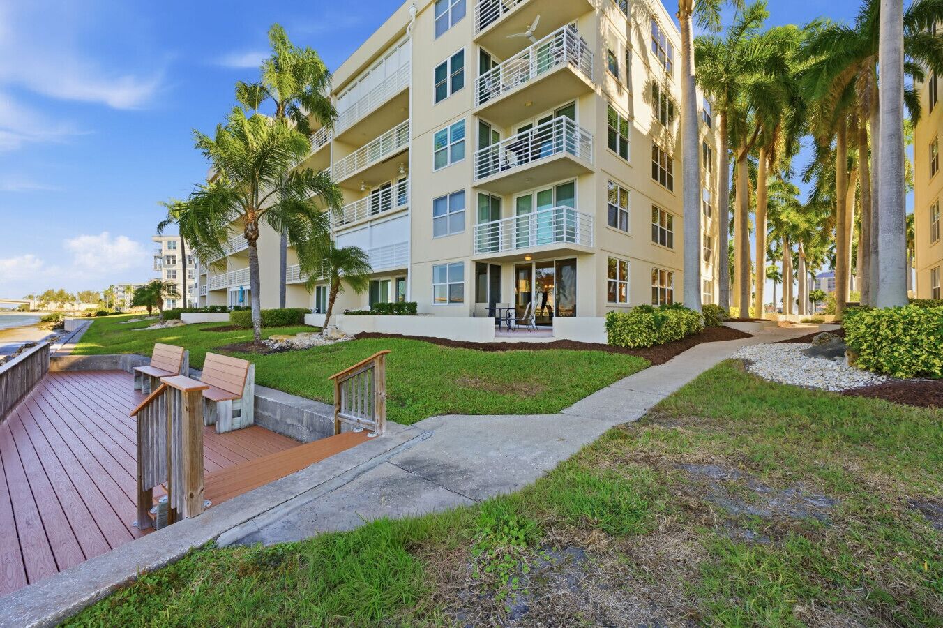A multi-story hotel with balconies, a deck area with seating, and palm trees.