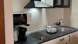 A modern kitchen with a black range hood, a built-in microwave, a coffee maker, and a sink with a black faucet. - Loft Eira Cálm&luxury Views Sierra Nevad Parking included (Sierra nevada)
