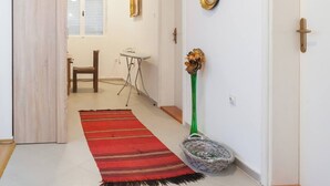 Un couloir avec un tapis rouge, un vase vert et un panier en osier.