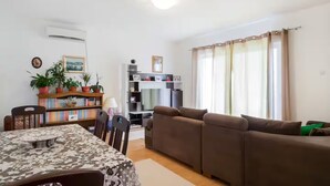 A living room with a sofa, a dining table with chairs, a bookshelf, and a television. - Giant 3-bedroom house in Susanj,Bar Montenegro (Šušanj)