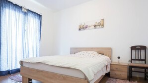 A bedroom with a wooden bed, a nightstand, a chair, and a painting on the wall. - Giant 3-bedroom house in Susanj,Bar Montenegro (Šušanj)