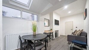 Uma sala de estar moderna com área de jantar, lareira e um sofá.
