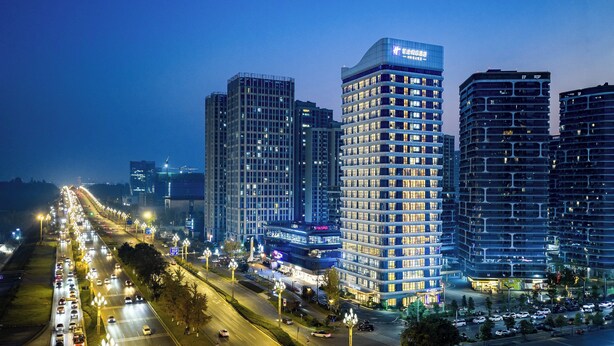 A high-rise hotel with multiple floors, a prominent sign at the top, and a busy street in the foreground. - Holiday Inn Express Chengdu Phoenix Mountain By Ihg (Chengdu)