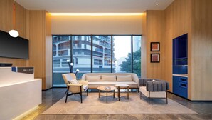 A modern hotel lobby with a sofa, chairs, a coffee table, and a reception desk. - Holiday Inn Express Chengdu Phoenix Mountain By Ihg (Chengdu)
