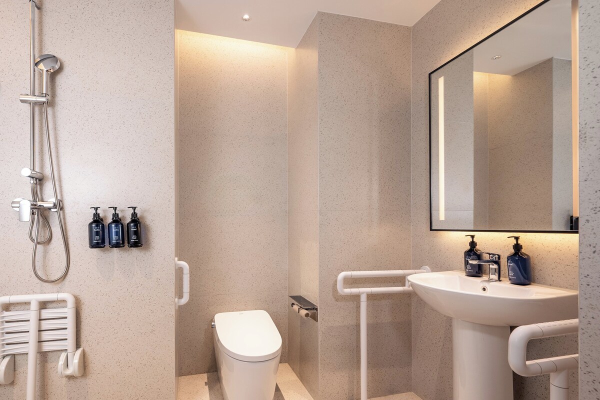 A modern bathroom with a shower, toilet, and sink.