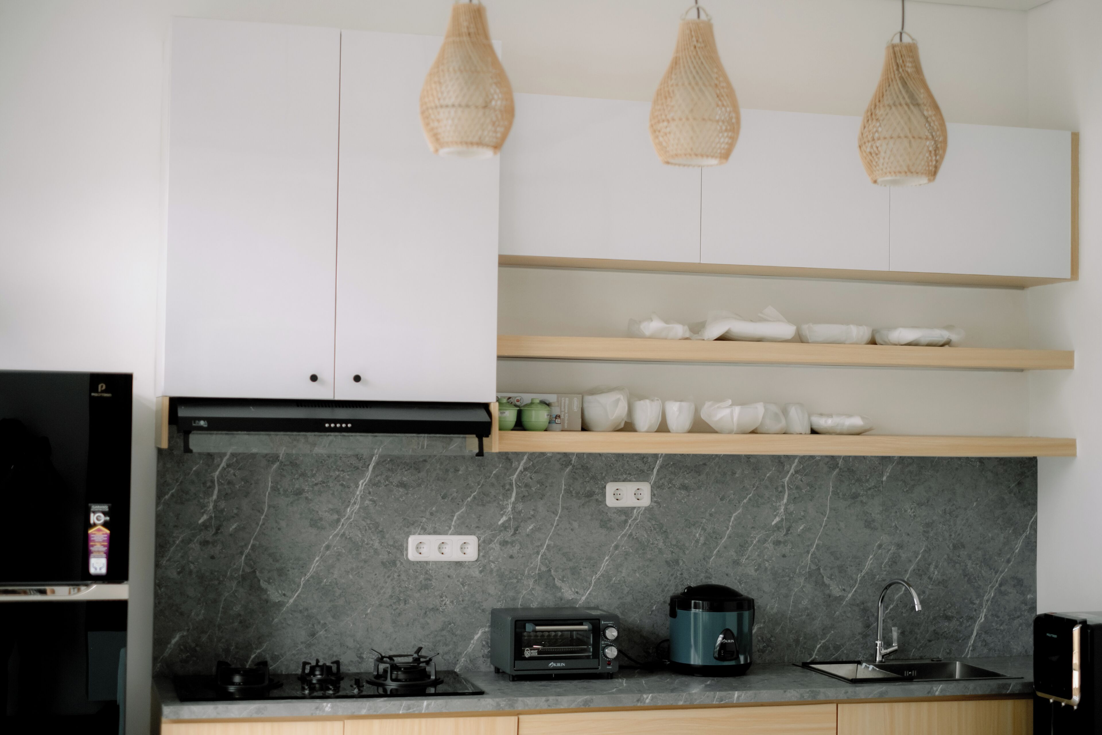 Eine moderne Küche mit Gasherd, Toaster, Kaffeemaschine und Spüle. Es gibt Korbtropf đèn und eine Marmor-Spritzschutzwand.