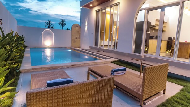 A modern house with a swimming pool, wicker furniture, and a well-lit interior. - Casa Verona Villa Lovina Bali (Buleleng)
