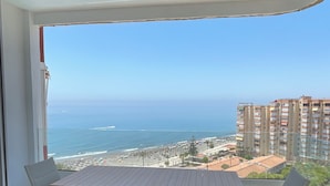 Ein Balkon mit Tisch und Stühlen, der Blick auf einen Strand und den Ozean freigibt.