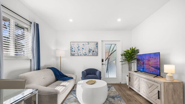Una sala de estar moderna con sofá, sillón, mesa de centro, televisor y plantas decorativas.
