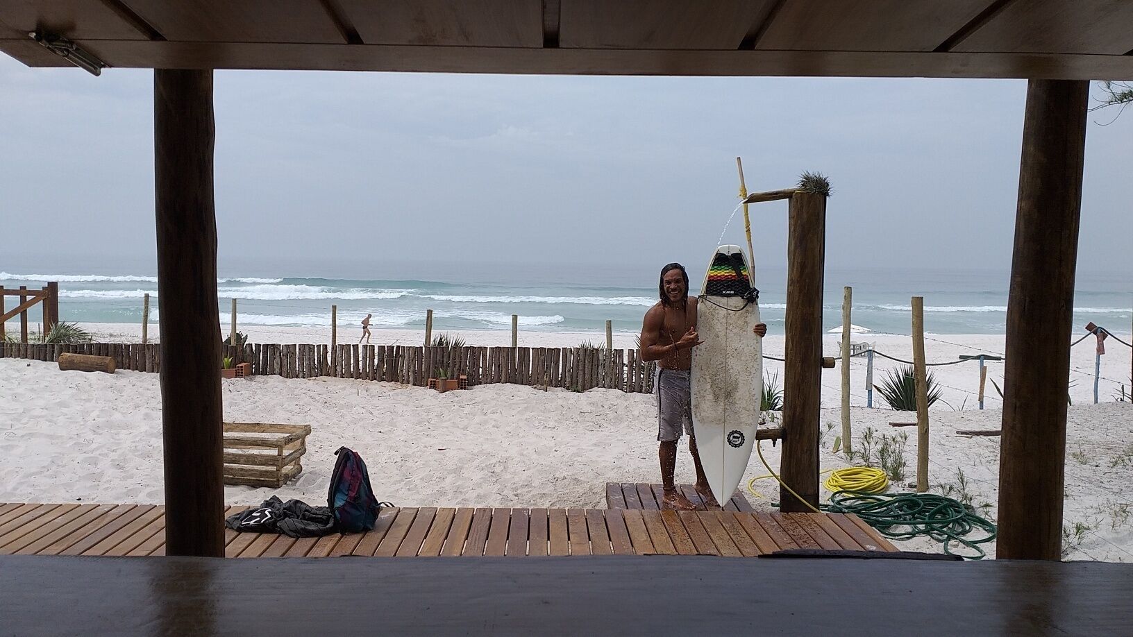 A wooden deck with a surfboard leaning against a wooden post.