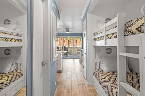 A corridor with bunk beds on either side, leading to an outdoor area with a table and chairs. - Island Casita W/ Pool & Beach Views & Sleeps 6! (Galveston)