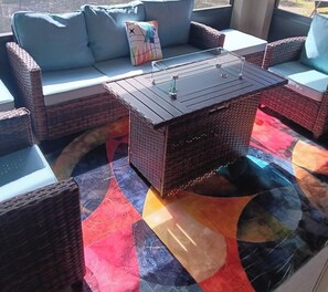 A wicker sofa with cushions, a matching armchair, and a small table with a glass top. - Charming 3-bedroom retro style house with game room and many amenities. (Punta Gorda)