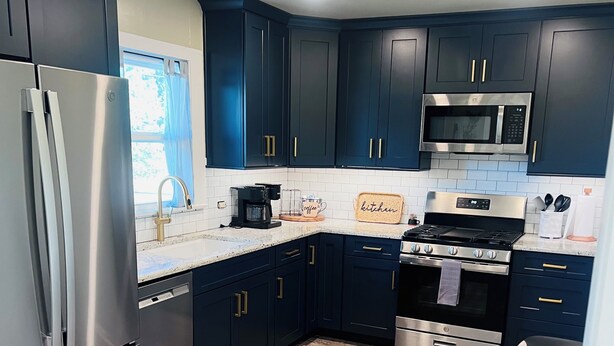 A modern kitchen with dark cabinets, stainless steel appliances, and a tiled floor. - Cozy 2-bedroom house in Enid (Enid)